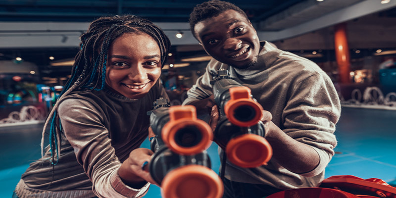 African american couple with black guns in arcade.